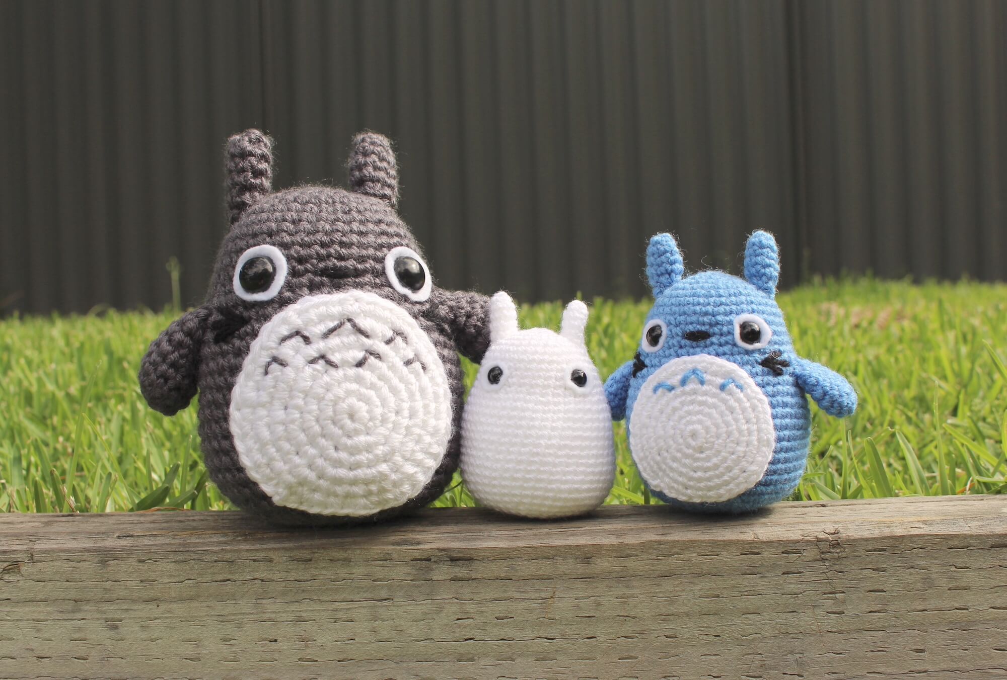 Three handmade crocheted amigurumi toys displayed on a wooden surface, colorful and detailed.